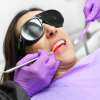 female with protective dark glasses undergoing oral health care with diode laser 