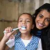 Child brushing teeth with adult